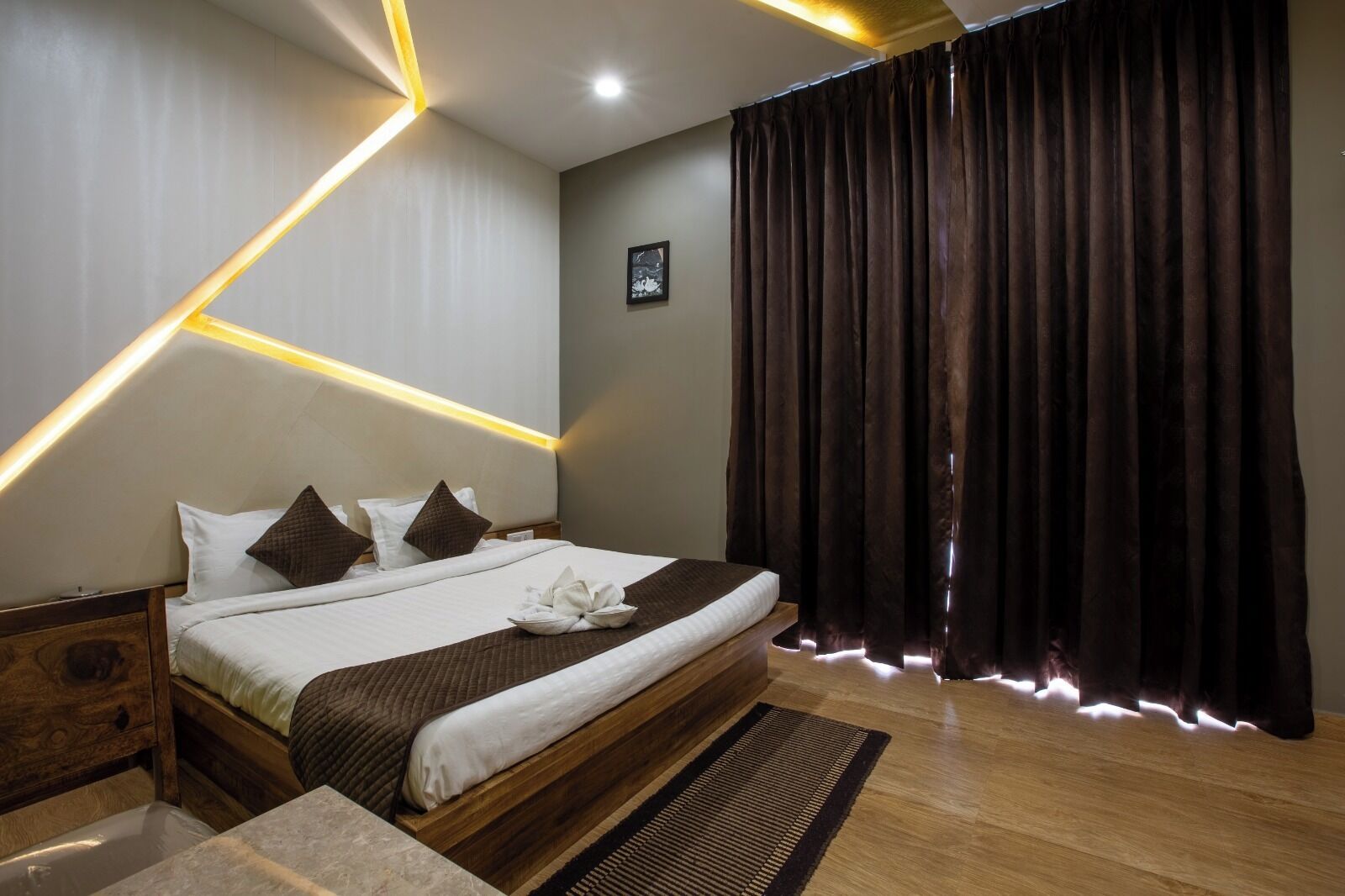 Een moderne hotelkamer met een groot bed, een houten hoofdbord en een donker gordijn.