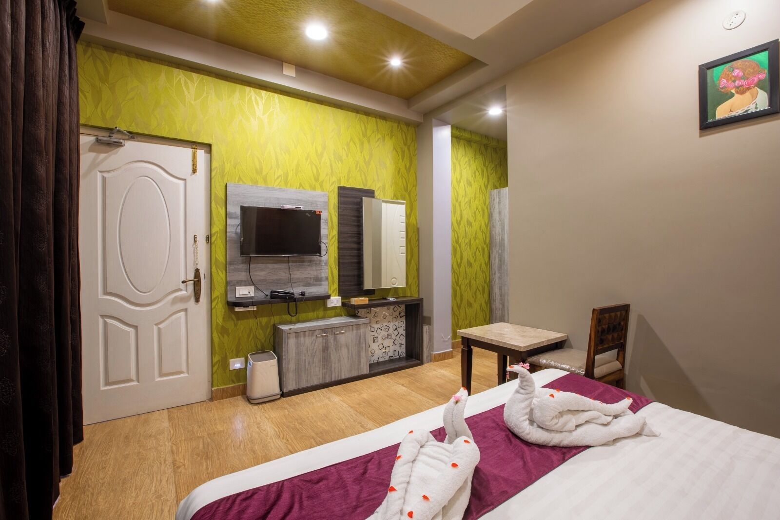 A hotel room with a bed, a TV mounted on the wall, a small table, and a chair.