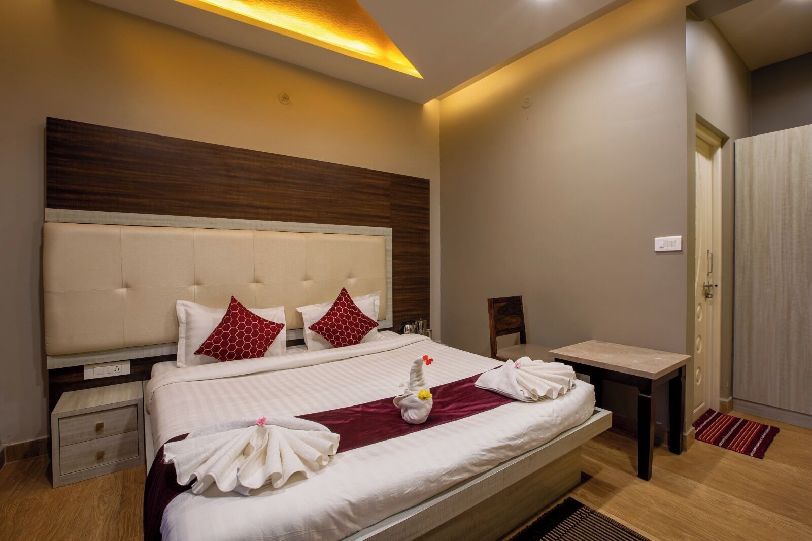 Una habitación de hotel con una cama grande, una mesita de noche, una silla y una puerta.