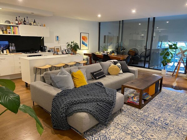 Relax in this stylish living room with a sofa, coffee table, and dining area, offering a view of the outdoors.