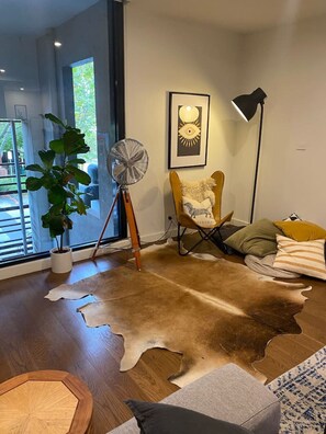 Relax in this stylish living room with a large rug, a potted plant, and a view of the outdoors.