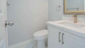 A bathroom with a white toilet, a sink with a gold faucet, and a mirror with a gold frame.