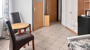 Une pièce de taille modeste comprenant une table à manger en bois, une chaise, une armoire et un coin cuisine.