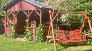 Une cabane en bois rustique, dotée d’une véranda, d’une balançoire et de jardinières fleuries.
