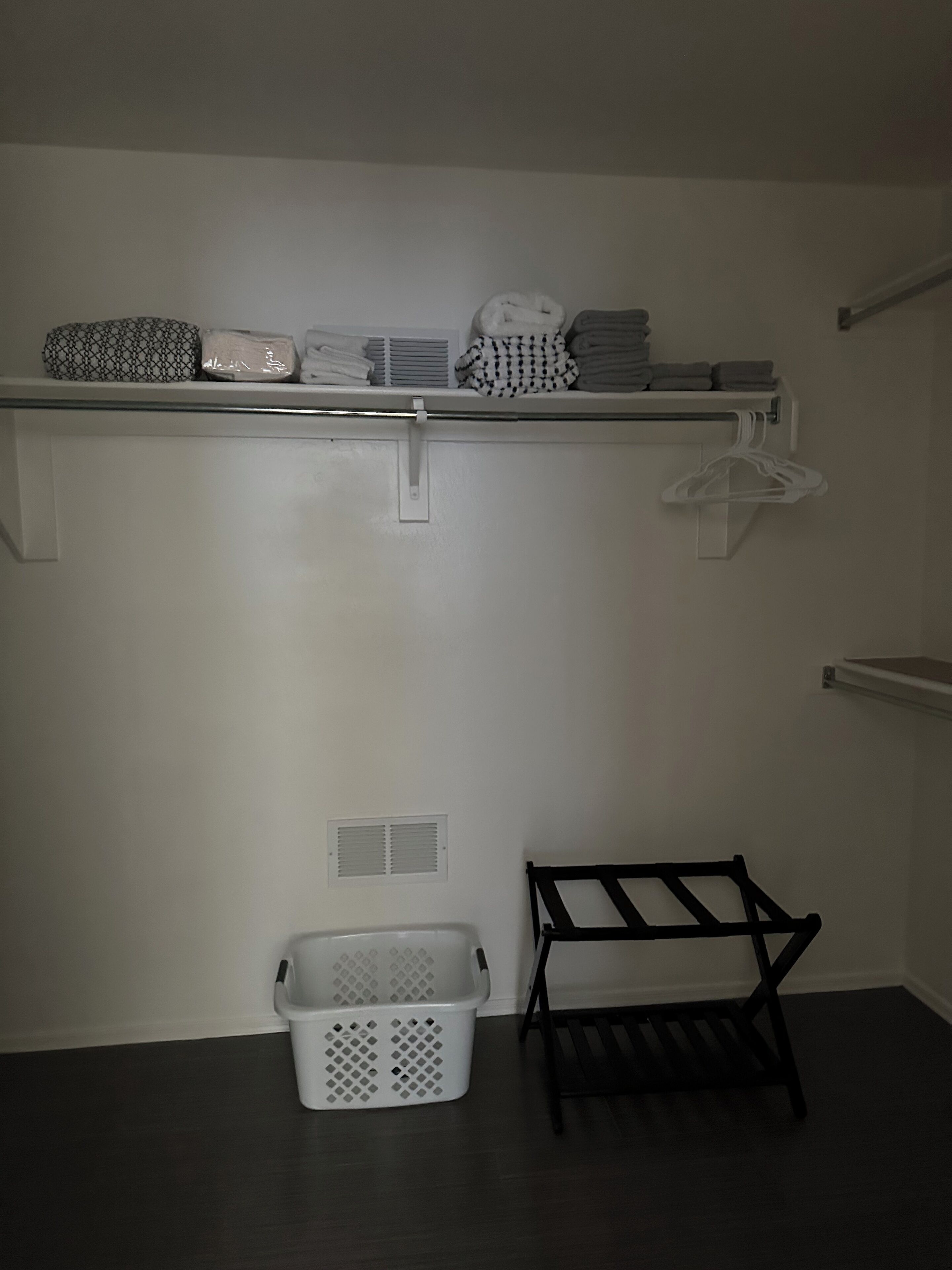 A laundry area with a shelf holding folded towels and a basket.