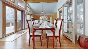 A dining room with a wooden table set for four, flanked by chairs with cushioned seats. - Charming lakefront cottage on Little Doe Lake in Muskoka area (Katrine)