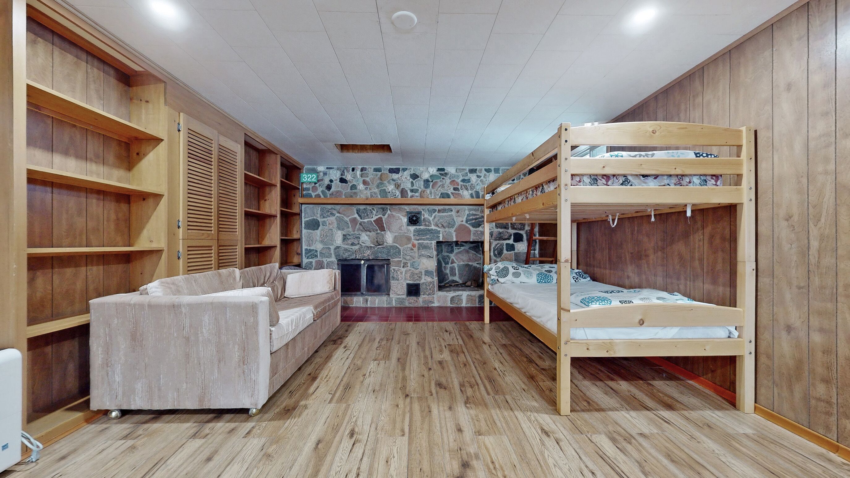 Una habitació amb llits superposats, un sofà i una llar de pedra.