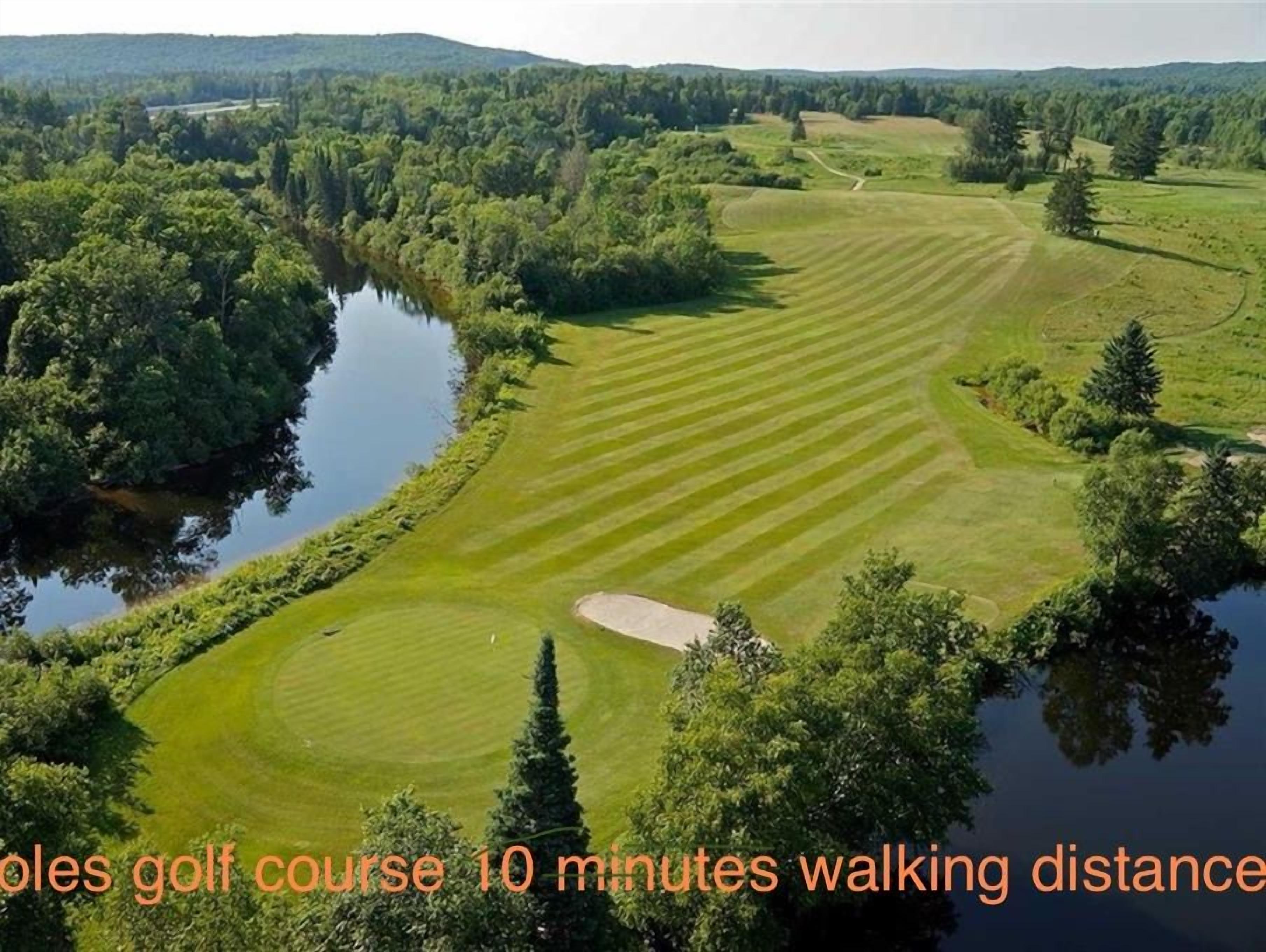 En golfbana med 18 hål, omgiven av frodig grönska och en vattenyta.