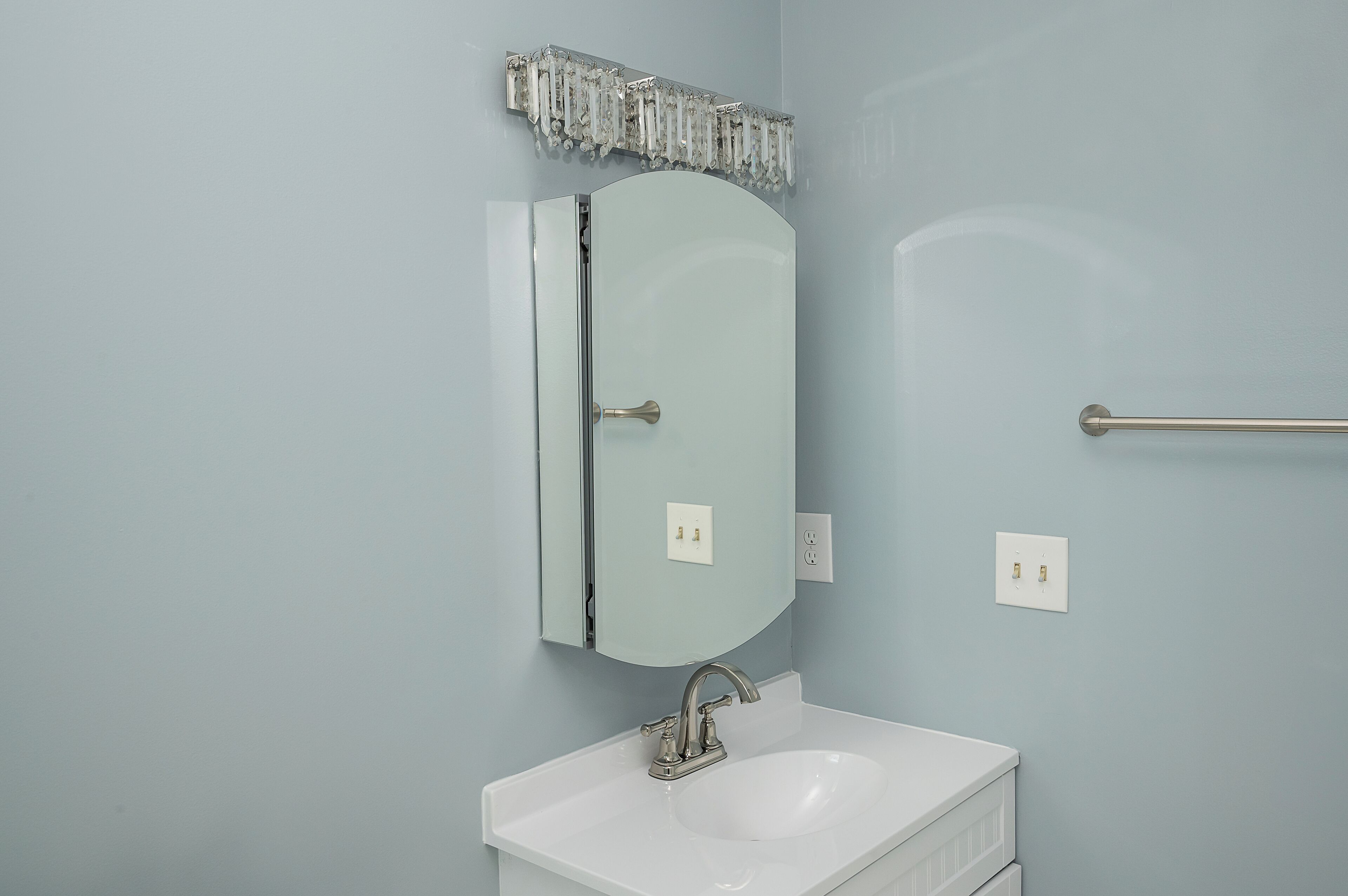 A bathroom with a white sink, a mirror, and a towel rack.