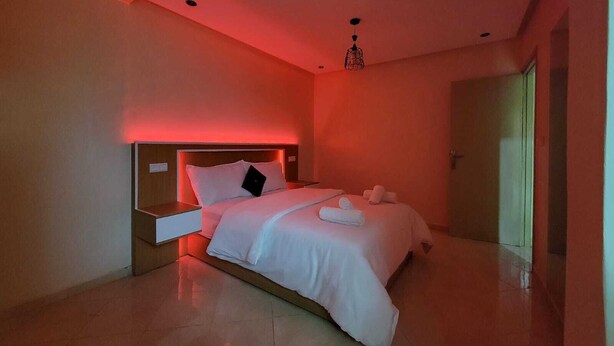 Ein modernes Hotelzimmer mit einem Bett, einem Nachttisch und einer Hängelampe.