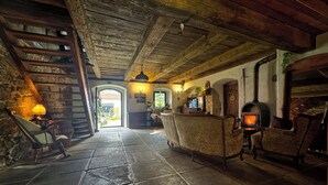 A rustic interior with stone walls, wooden beams, a stone floor, a fireplace, and a stone staircase. - The Oak Lodge (Lwowek Slaski)