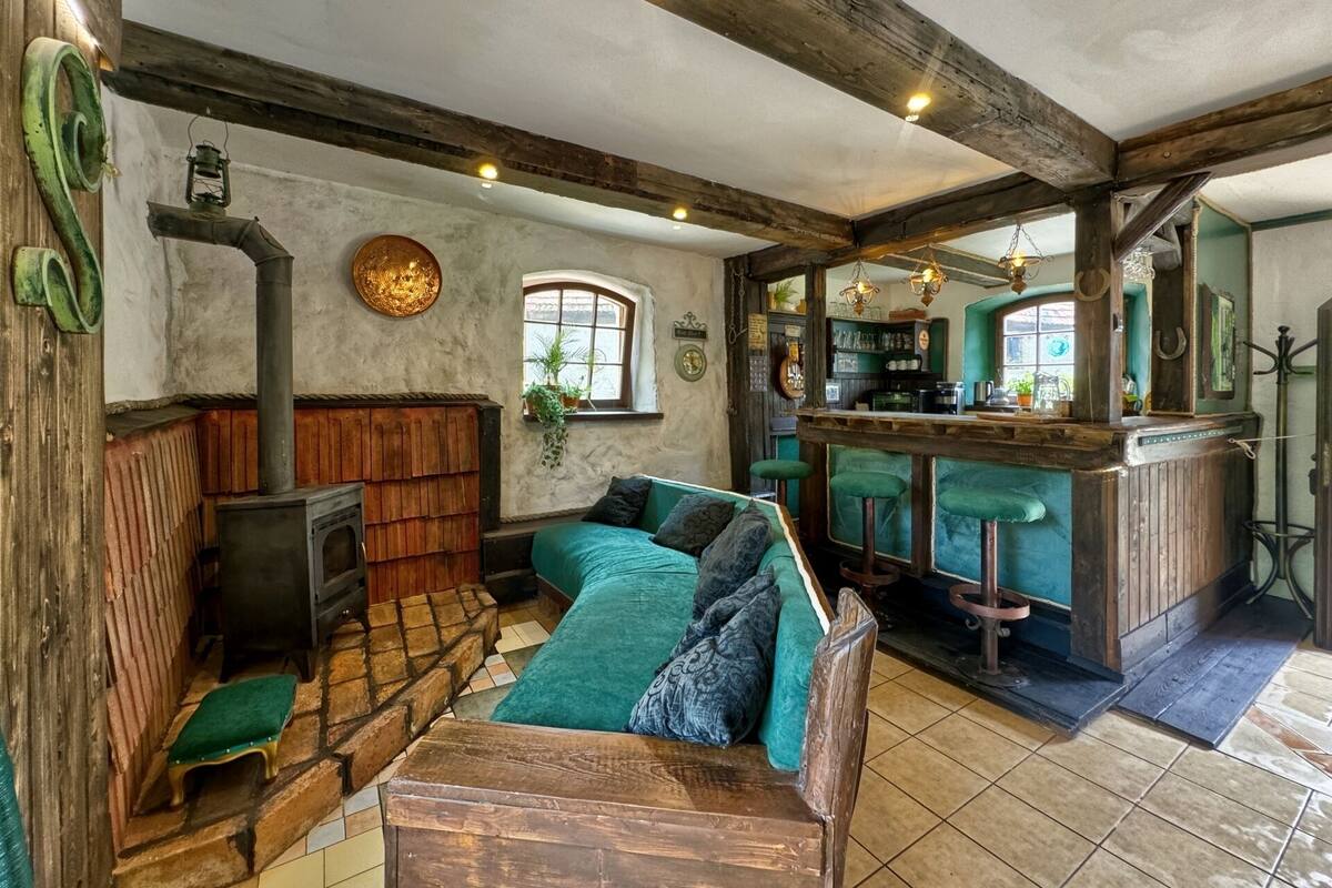 A rustic interior with a wooden bench, a sofa, a bar area, and a fireplace.