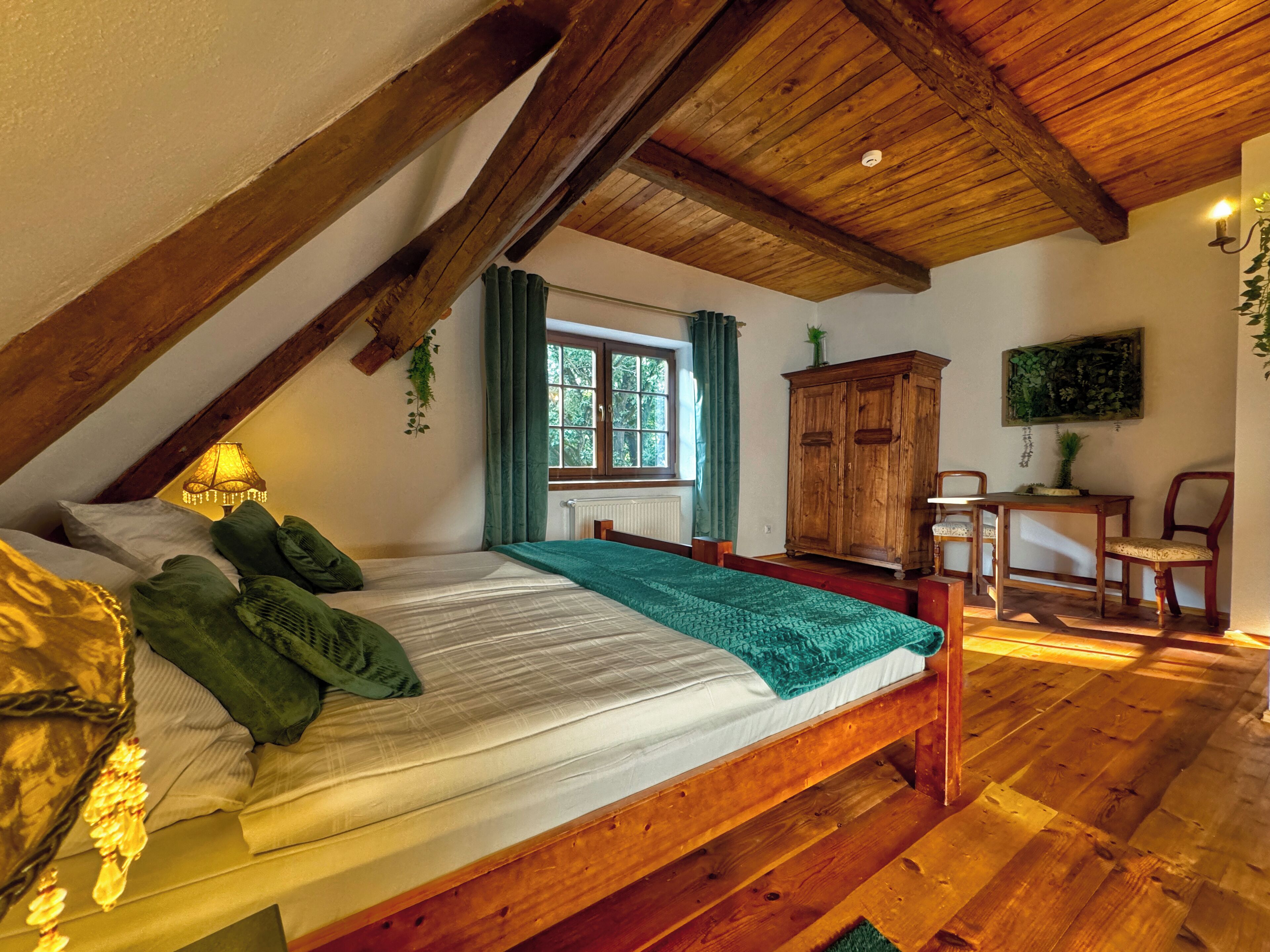 A bedroom with a wooden bed, a window with curtains, a wooden cabinet, and a table with chairs.