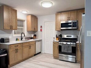 A kitchen with wooden cabinets, a stainless steel microwave, a gas stove, and a dishwasher.
