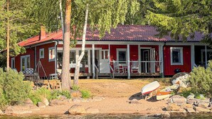 A red cabin with a porch, surrounded by trees and a lake. - Awesome home in Hultsfred with sauna (Hultsfred)