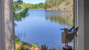 A view of a calm lake from a window with a rustic wooden door and a metal sculpture. - Awesome home in Hultsfred with sauna (Hultsfred)