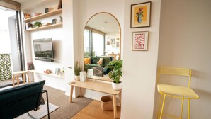 A modern living room with a sofa, a coffee table, a TV, and a yellow chair. - Eclectic City-Fringe Townhouse with Rooftop Deck (Auckland)