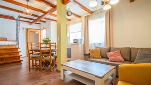 A living room with wooden floors, a sofa, a yellow armchair, a dining table with chairs, and a staircase. - 2 bedroom stunning apartment in Veli Brgud (Veli Brgud)