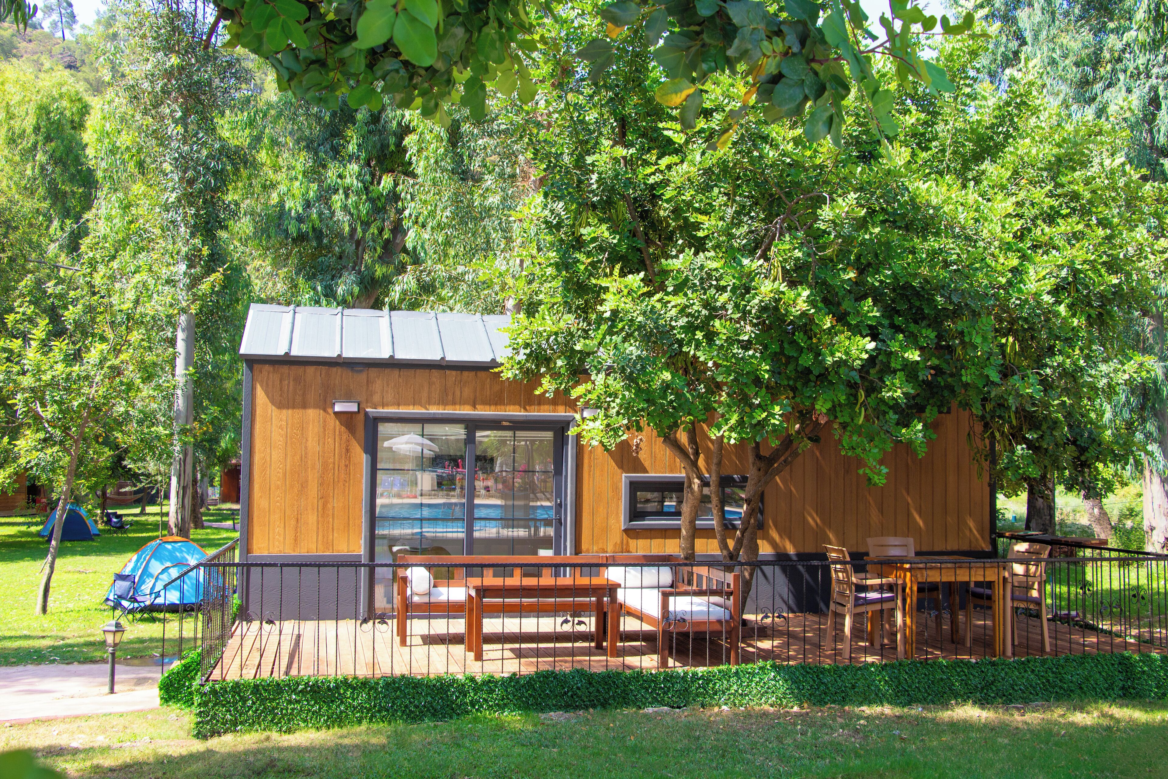 A wooden cabin with a deck, large windows, and outdoor seating.