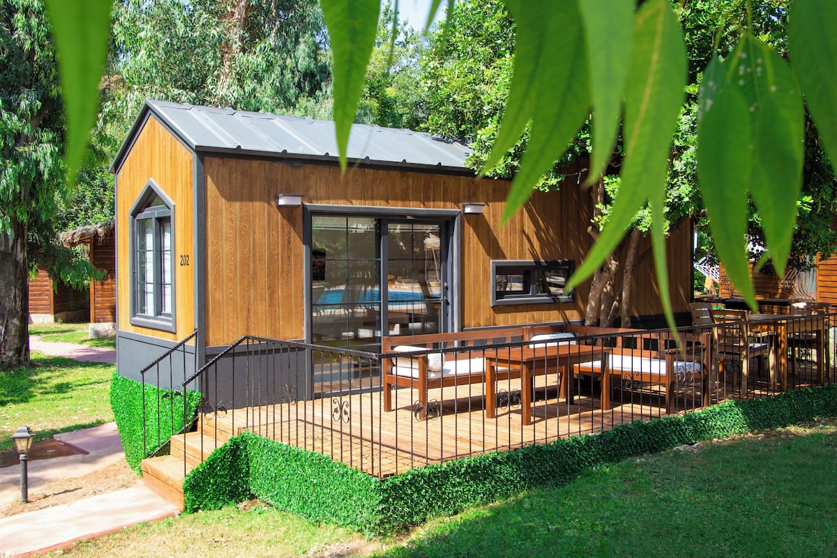 Una cabaña de madera con un balcón, un ventanal grande y una puerta.