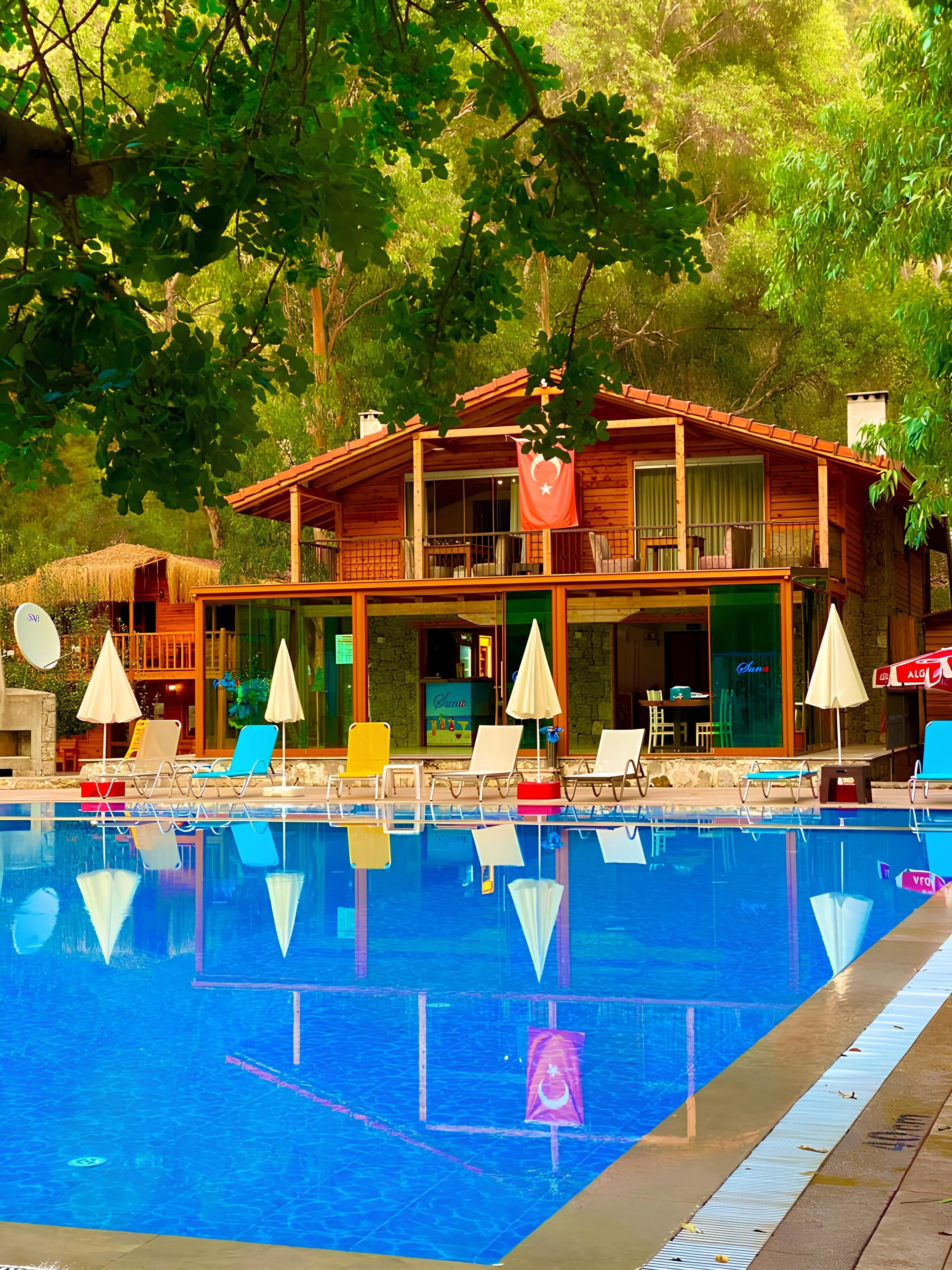 A wooden building with a pool, lounge chairs, and umbrellas.