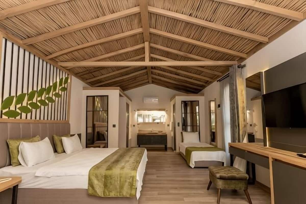 Habitación de hotel con techo alto, cama, escritorio y televisión.
