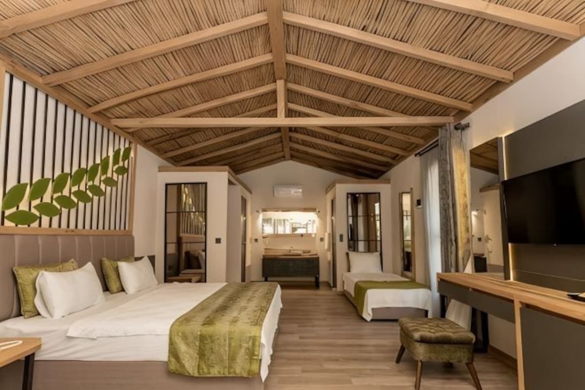 Habitación de hotel con techo alto, cama, escritorio y televisión.