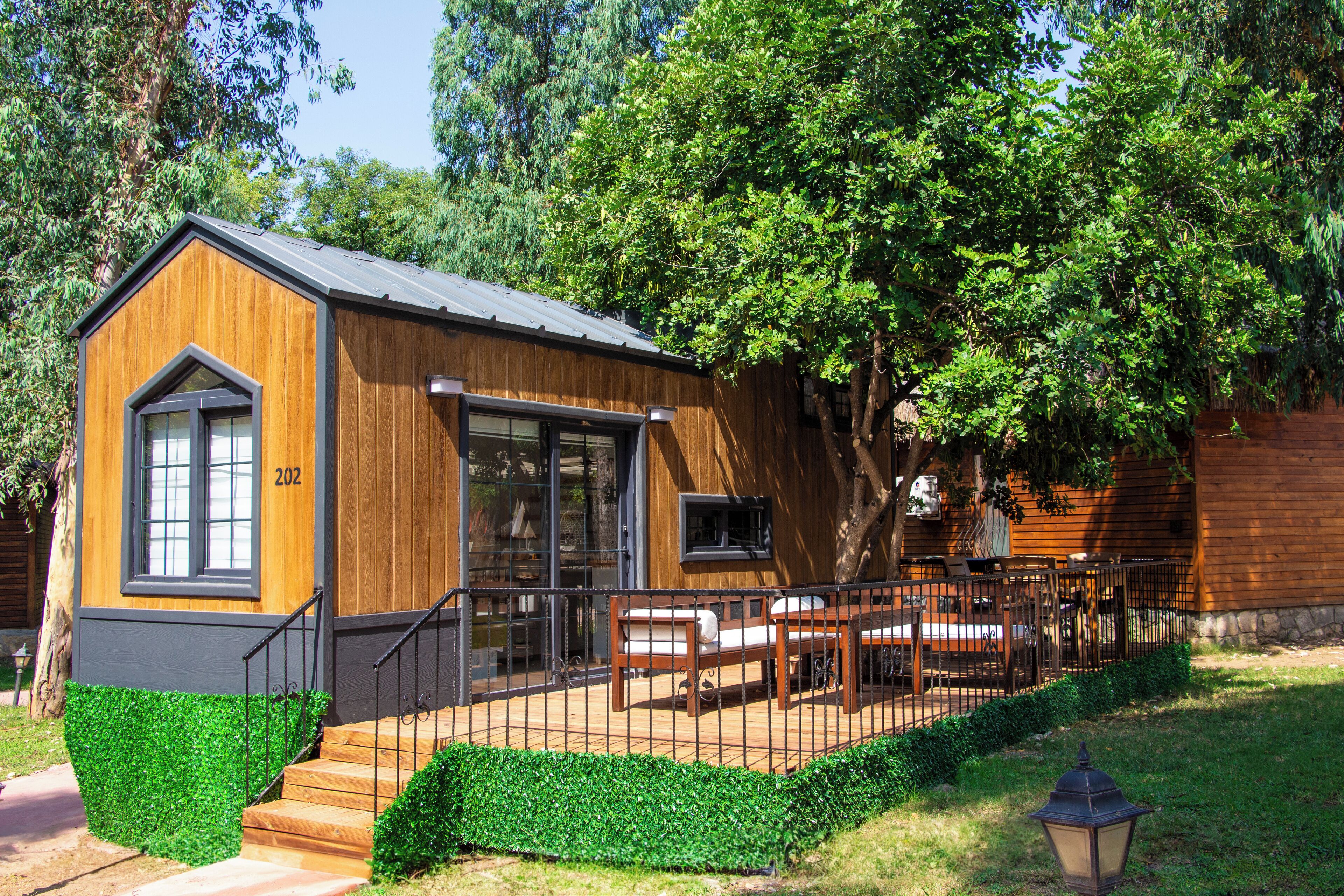 A wooden cabin with a large window, a door, and a small porch area with a bench.