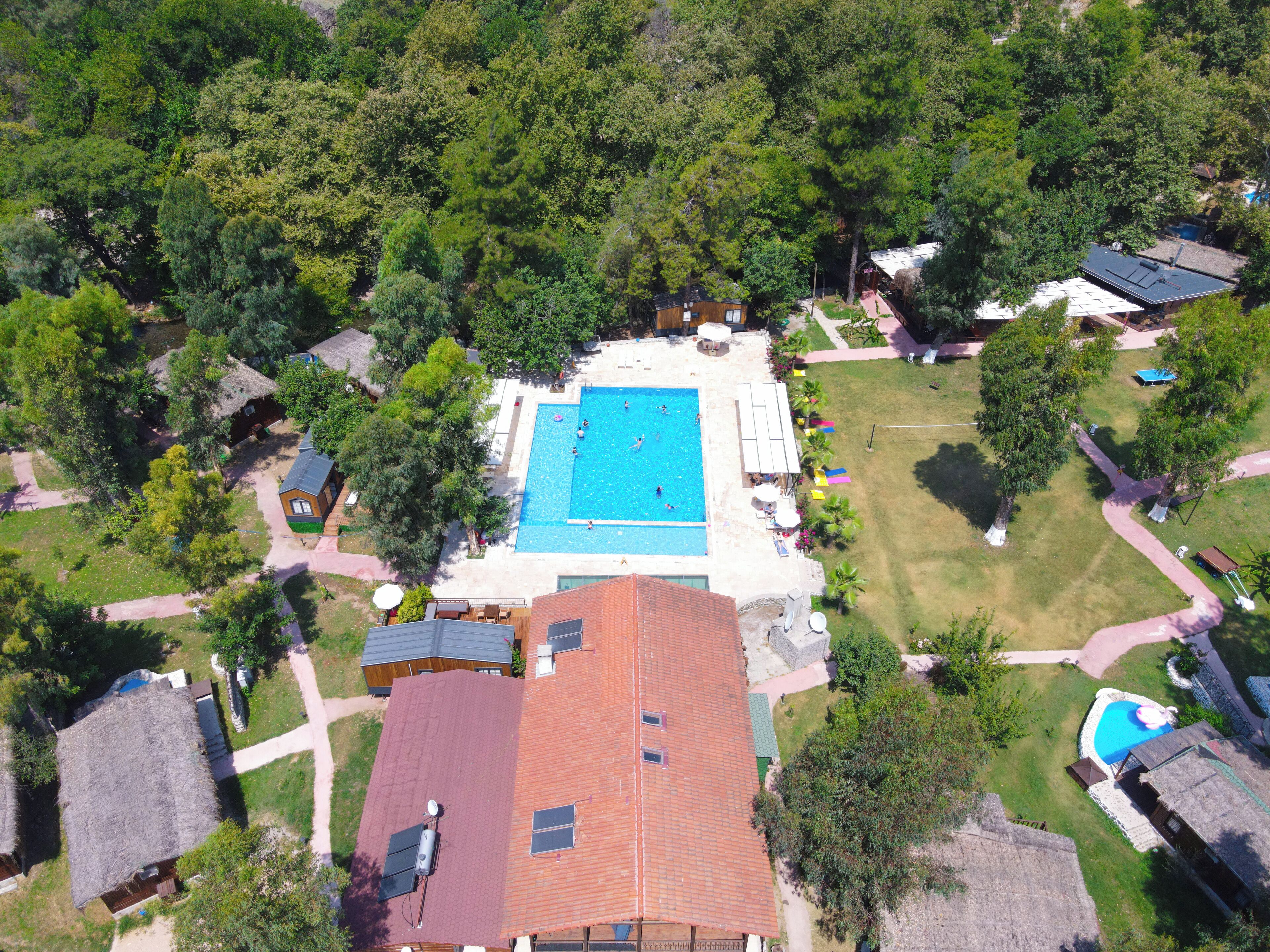 Vista aérea de una zona residencial con piscina, casas y abundante vegetación.