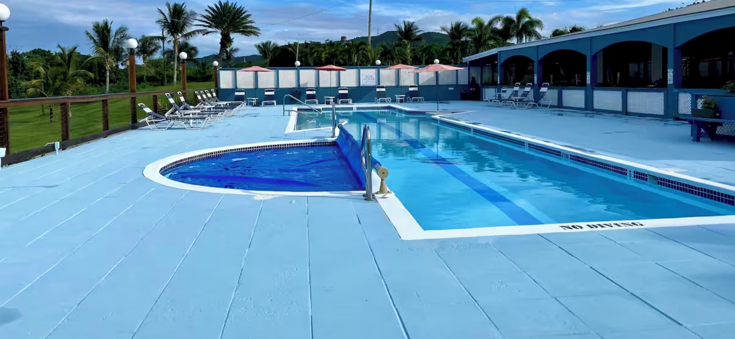 A pool area with a hot tub, lounge chairs, and a covered seating area.