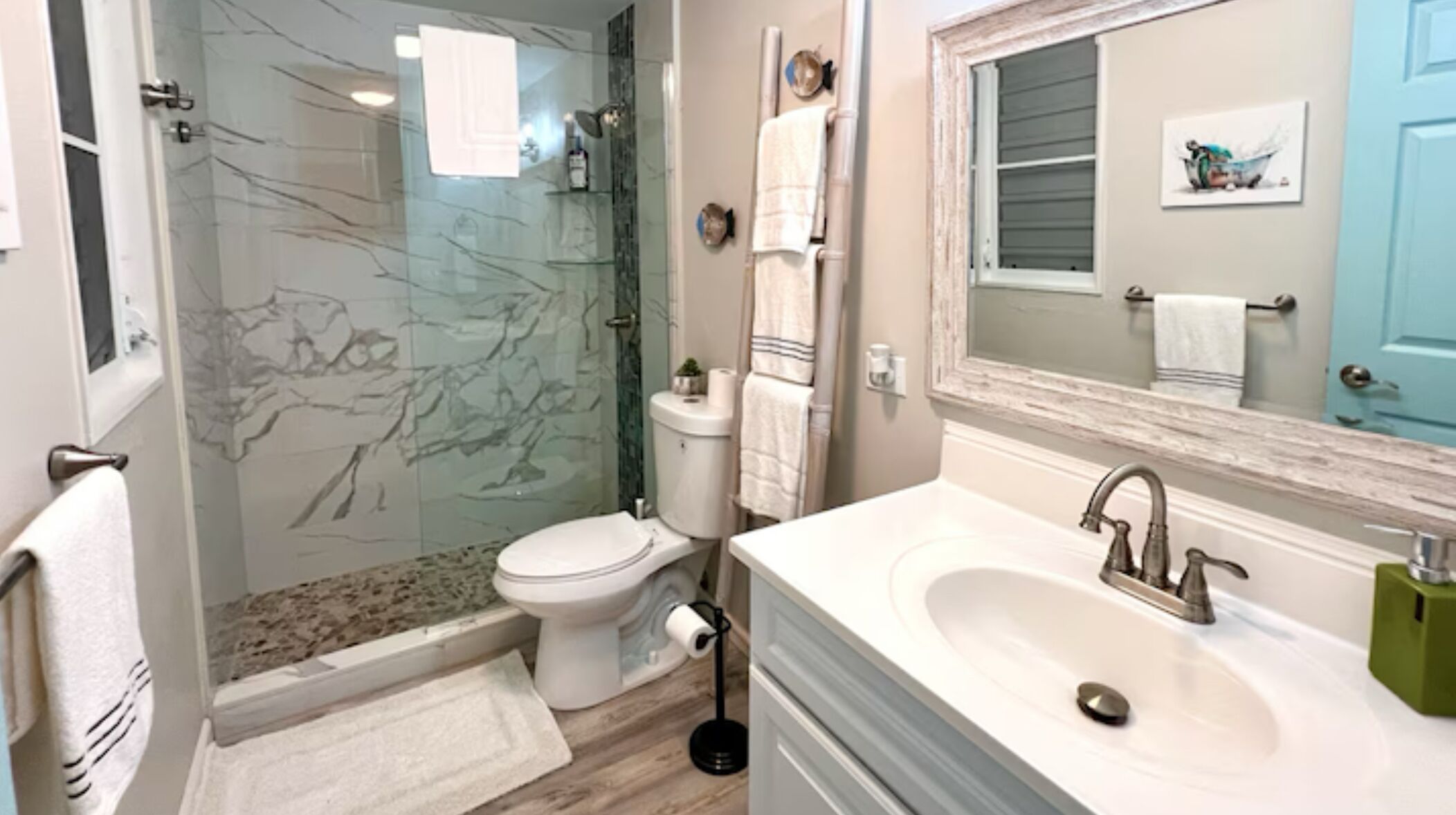 Un baño con cabina de ducha de vidrio, inodoro, lavabo y espejo.