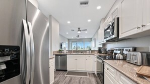 Una cucina moderna con elettrodomestici in acciaio inossidabile, mobili bianchi e pavimento in legno.