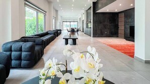 Un vestíbulo amplio con una extensa zona de estar, una mesa central y una chimenea.