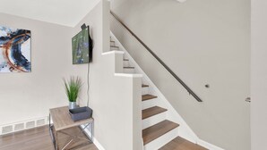 A modern staircase with a handrail, a wooden floor, a small table with a plant, and a framed picture on the wall. - Birmingham Retreat - Relax & Enjoy (Birmingham)