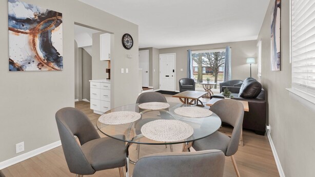 A modern living room with a glass dining table, grey sofas, and a large abstract painting. - Birmingham Retreat - Relax & Enjoy (Birmingham)