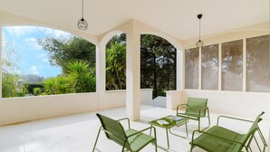 Een ruime kamer met witte wanden, grote ramen en groene metalen stoelen.