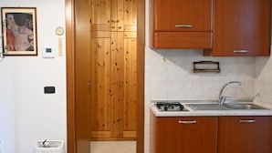 Eine Küche mit Holzschränken, einem Gasherd, einem Spülbecken und einer gefliesten Rückwand.