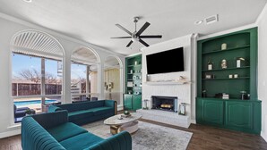 Un salon spacieux avec un canapé de couleur turquoise, une cheminée et un téléviseur fixé au mur.