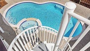 Une piscine avec une terrasse blanche et un petit jacuzzi.
