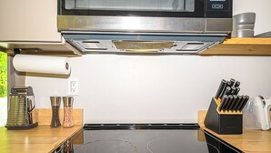 Una cocina con estufa de acero inoxidable, un microondas encima y una encimera de madera.