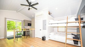 Habitación compacta con una cama nido, kitchenette, ventilador de techo y vistas a zonas verdes.