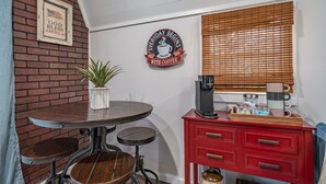 Een compact keukenhoekje met een rode kast, een koffieapparaat en een bordje met de tekst 