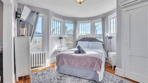 Et soveværelse med seng, radiator, vindue og et natbord.