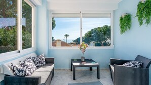 Ein sonnendurchflutetes Zimmer mit Meerblick, ausgestattet mit einer Couch, einem kleinen Tisch und einem Blumentopf.