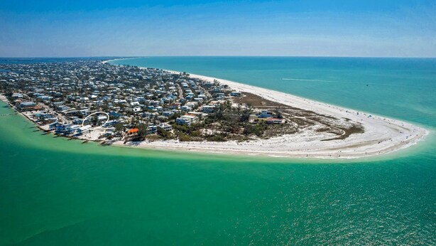 An aerial view of a coastal town with a beach, houses, and clear turquoise waters. - Dolce Vita: Amazing Rooftop Experience, Views, Pool, Spa by Anna Maria Life Vacation Rentals (Anna Maria)