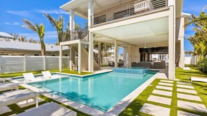A modern two-story house with a swimming pool, outdoor seating, and a covered patio area. - Dolce Vita: Amazing Rooftop Experience, Views, Pool, Spa by Anna Maria Life Vacation Rentals (Anna Maria)