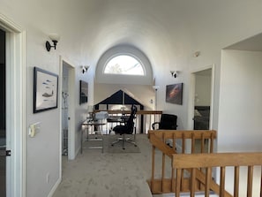 A spacious hallway with a high ceiling, a wooden staircase, and a skylight.