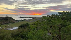 Eine Küstenlandschaft mit Sonnenuntergang, Grasflächen und einer Straße, die zum Meer führt.