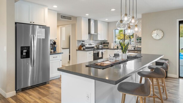 A modern kitchen with a stainless steel refrigerator, a central island with bar stools, and pendant lighting. - Scottsdale Day Dream - Spacious modern home with Private Pool, Hot Tub, and Firepit (Scottsdale)