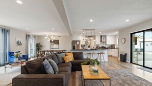 A modern living room with a sofa, coffee table, and dining area. - Scottsdale Day Dream - Spacious modern home with Private Pool, Hot Tub, and Firepit (Scottsdale)